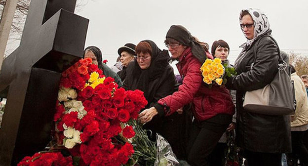 People laying flowers in memory of the terror act victims. Photo:  https://upload.wikimedia.org/wikipedia/commons/thumb/0/0d/Krest_poklonnyi_terakt.JPG/640px-Krest_poklonnyi_terakt.JPG