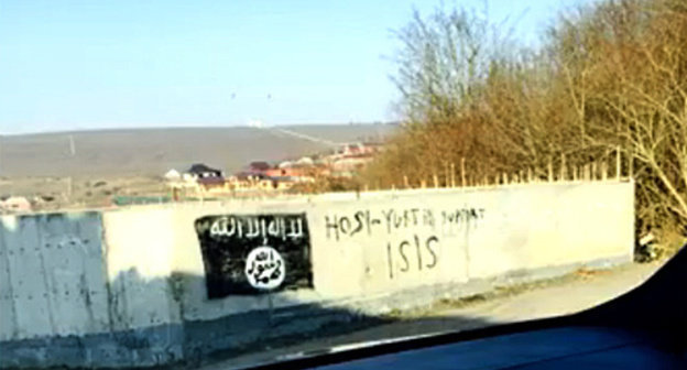 An image of the flag used by the militants of the "Islamic State" (recognized on December 29, 2014, by the Supreme Court of the Russian Federation as a terrorist organization) on a wall of the building in the village of Khosi-Yurt. Photo: screenshot of a video ISIS in Khosi-Yurt / IG in Chechnya, http://www.youtube.com/watch?v=n2sVCqLfPp0 An image of the flag used by the militants of the "Islamic State" (recognized on December 29, 2014, by the Supreme Court of the Russian Federation as a terrorist organization) on a wall of the building in the village of Khosi-Yurt. Photo: screenshot of a video ISIS in Khosi-Yurt / IG in Chechnya, http://www.youtube.com/watch?v=n2sVCqLfPp0