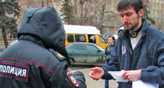 Police officer checking document of activist Yury Trotsenko during solo picket. Volgograd, March 7, 2015. Photo by Vyacheslav Yaschenko for the ‘Caucasian Knot’. Police officer checking document of activist Yury Trotsenko during solo picket. Volgograd, March 7, 2015. Photo by Vyacheslav Yaschenko for the ‘Caucasian Knot’.