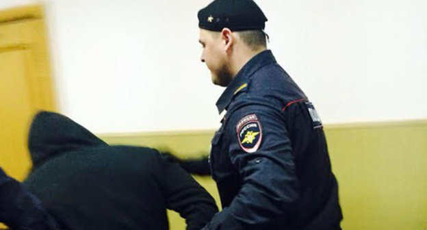 Law enforcer escorting defendant in Boris Nemtsov murder case. Basmanny District Court of Moscow, April 6, 2015. Law enforcer escorting defendant in Boris Nemtsov murder case. Basmanny District Court of Moscow, April 6, 2015.