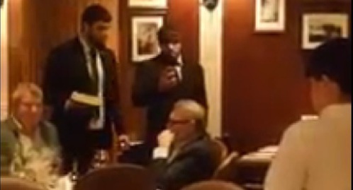 Two men who attacked Mikhail Kasyanov standing with a cake near the politician at a Moscow restaurant. Screenshot of a video of the attack on the site tv.mk.ru