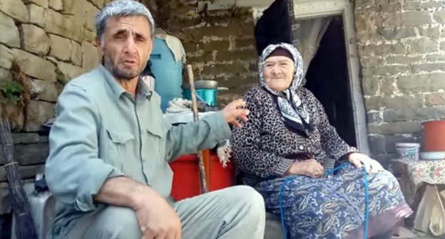 Ramazan Djalaldinov sit near the elderly resident of Kenkhi village. Photo: screenshot of the video appeal. Ramazan Djalaldinov sit near the elderly resident of Kenkhi village. Photo: screenshot of the video appeal.