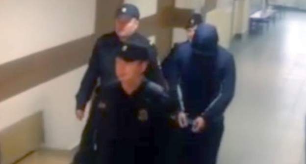 Policemen accompany Magomed Guchigov to the court hearings. Screenshot of video coverage by NTV channel, Ntv.ru/video Policemen accompany Magomed Guchigov to the court hearings. Screenshot of video coverage by NTV channel, Ntv.ru/video