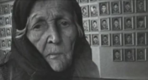 An elderly woman near the photos of the victims of war and deportation. Photo: screenshot of the video on the YouTube channel vainakh38 An elderly woman near the photos of the victims of war and deportation. Photo: screenshot of the video on the YouTube channel vainakh38