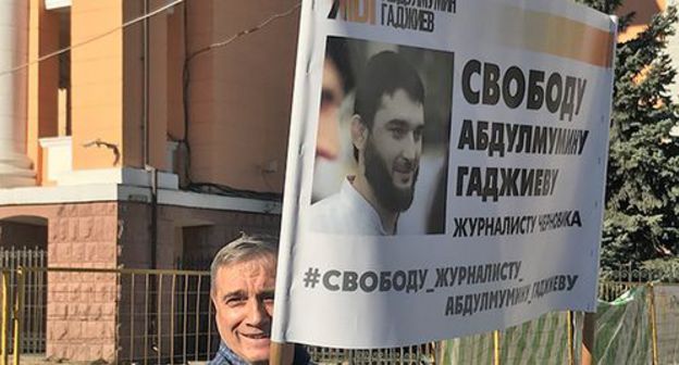 A resident of Makhachkala with a poster in support of Abdulmumin Gadjiev. Makhachkala, October 2019. Photo by Patimat Makhmudova for the "Caucasian Knot" A resident of Makhachkala with a poster in support of Abdulmumin Gadjiev. Makhachkala, October 2019. Photo by Patimat Makhmudova for the "Caucasian Knot"