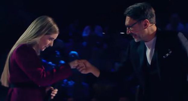 Sergey Shnurov took Ragda Khanieva by the hand in "The Voice" song show. Screenshot of the video on YouTube Голос / The Voice Russia https://www.youtube.com/watch?v=B5BVyY6glCQ&feature=youtu.be Sergey Shnurov took Ragda Khanieva by the hand in "The Voice" song show. Screenshot of the video on YouTube Голос / The Voice Russia https://www.youtube.com/watch?v=B5BVyY6glCQ&feature=youtu.be