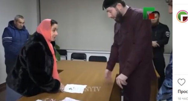 Petimat Suleimanova and Adam Elzhurkaev in the "Grozny" ChGTRK TV story. Screenshot from ChGTRK's Instagram post: https://www.instagram.com/p/B6ssDCwCIik/ Petimat Suleimanova and Adam Elzhurkaev in the "Grozny" ChGTRK TV story. Screenshot from ChGTRK's Instagram post: https://www.instagram.com/p/B6ssDCwCIik/