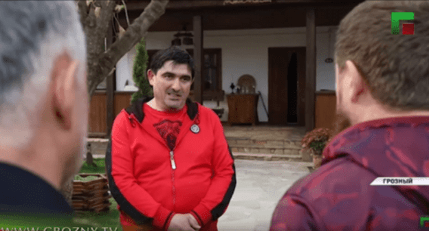 Aslanbek Akhmetkhanov (centre) standing in front of Ramzan Kadyrov (right). Screenshot from video broadcasting by ChGTRK 'Grozny', https://youtu.be/IUHeFy2cpfk Aslanbek Akhmetkhanov (centre) standing in front of Ramzan Kadyrov (right). Screenshot from video broadcasting by ChGTRK 'Grozny', https://youtu.be/IUHeFy2cpfk