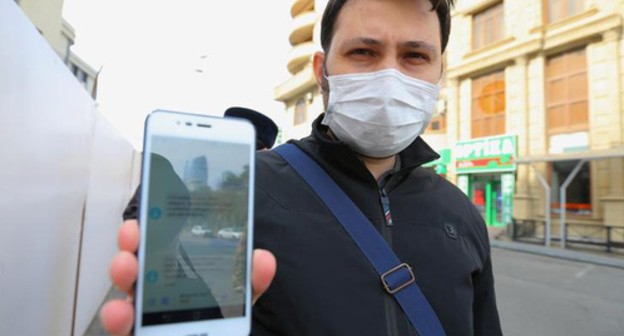 A resident of Baku shows an SMS permit for leaving home. Photo REUTERS/Aziz Karimov A resident of Baku shows an SMS permit for leaving home. Photo REUTERS/Aziz Karimov