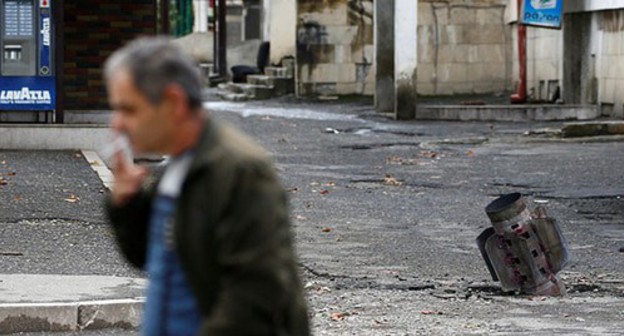 A resident of Stepanakert near an unexploded shell, October 2020. Photo: REUTERS/Stringer A resident of Stepanakert near an unexploded shell, October 2020. Photo: REUTERS/Stringer