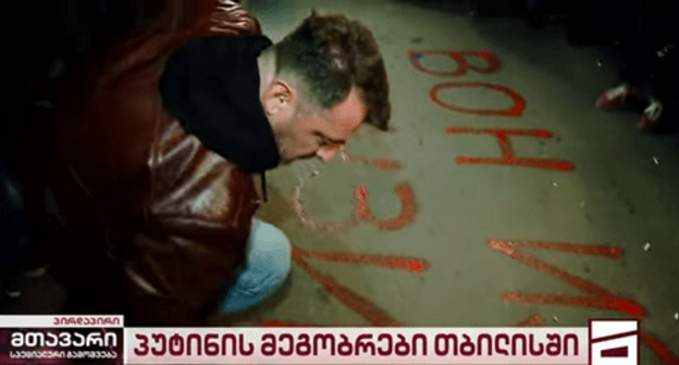 Protester writing on the asphalt: 'Posner, go out of Georgia!' Screenshot: Mtavari Arkhi Protester writing on the asphalt: 'Posner, go out of Georgia!' Screenshot: Mtavari Arkhi