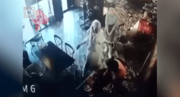 A conflict between Elez Merzhoev (dressed in orange) and Aina Getagazova (dressed in white) in a cafe in Nazran on June 15, 2021. Screenshot of the video https://dni.ru/video/2021/6/17/481045.html A conflict between Elez Merzhoev (dressed in orange) and Aina Getagazova (dressed in white) in a cafe in Nazran on June 15, 2021. Screenshot of the video https://dni.ru/video/2021/6/17/481045.html