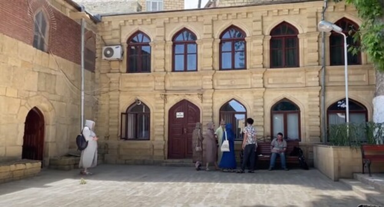 Tourists in a courtyard of a mosque in Derbent. Screenshot: https://www.youtube.com/watch?v=1rUg3LrF6kQ Tourists in a courtyard of a mosque in Derbent. Screenshot: https://www.youtube.com/watch?v=1rUg3LrF6kQ