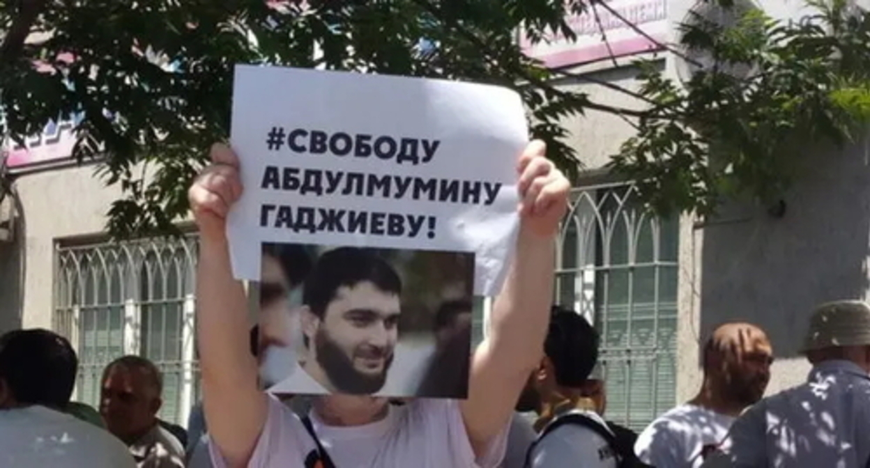 An activist holds a poster with the photo of Abdulmumin Gadjiev. Makhachkala, June 2019. Photo by Murad Muradov for the "Caucasian Knot" An activist holds a poster with the photo of Abdulmumin Gadjiev. Makhachkala, June 2019. Photo by Murad Muradov for the "Caucasian Knot"