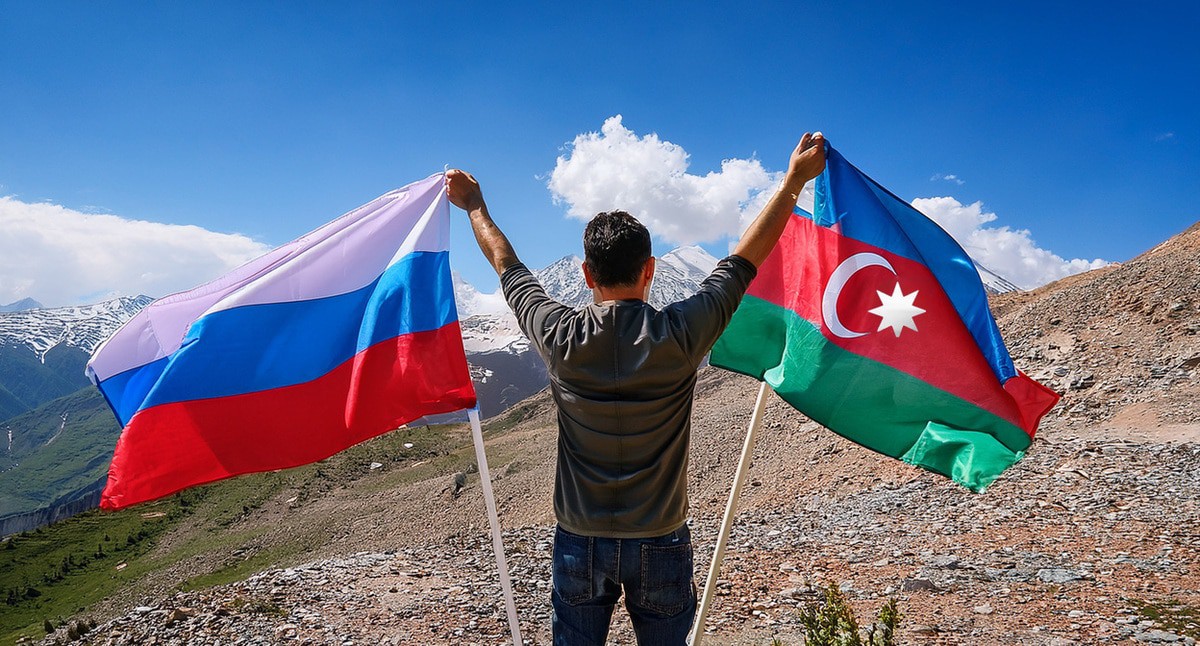 A man holds the flags of Russia and Azerbaijan. Picture made in Photoshop by the "Caucasian Knot"