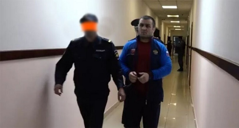 Security forces are leading Islam Atavov. Photo: "Chernovik" (the security force's face is retouched in the original publication https://chernovik.net/news/atavov-dayot-ne-sovsem-pravdivye-pokazaniya-i-vygorazhivaet-sebya-roditeli-ubitogo-v-sovetskom) Security forces are leading Islam Atavov. Photo: "Chernovik" (the security force's face is retouched in the original publication https://chernovik.net/news/atavov-dayot-ne-sovsem-pravdivye-pokazaniya-i-vygorazhivaet-sebya-roditeli-ubitogo-v-sovetskom)