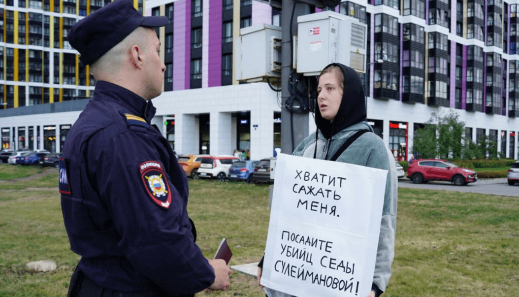 Lena Patyaeva talks to a police officer. Screenshot of the photo "A Word to the Defense" from 23.08.25, https://t.me/endoflaw/1183.