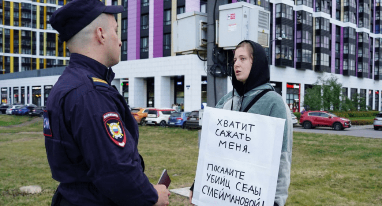 Lena Patyaeva talks to a police officer. Screenshot of the photo "A Word to the Defense" from 23.08.25, https://t.me/endoflaw/1183.