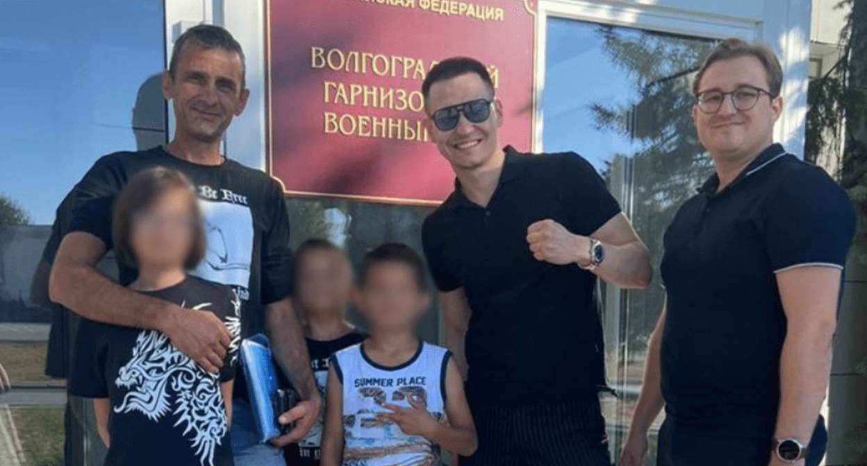 Ruslan Zhadaev (left) with children and protection. Screenshot of the photo "Height 102" from 31.08.25, https://v102.ru/news/147301.html