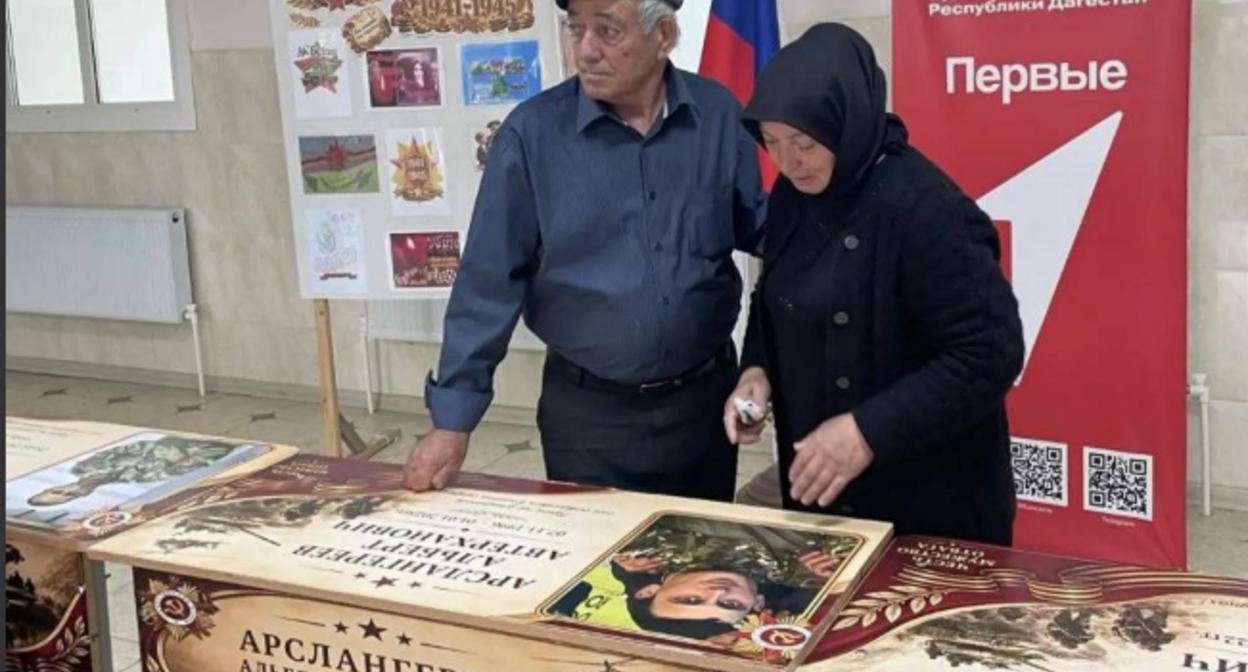 Relatives at the unveiling of a personalized desk. Screenshot from the Babayurt District Administration, May 25, 2026, https://t.me/babayurtrayon/12221?single