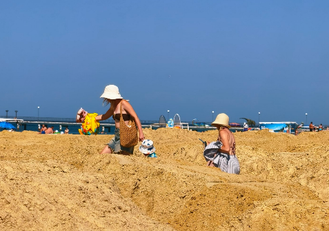 Tourists are making their way among the piles of sand to the beach in Vityazevo. Screenshot photo by Andrey Makovozov from 19.07.26, https://t.me/makovozovy/64553 Tourists are making their way among the piles of sand to the beach in Vityazevo. Screenshot photo by Andrey Makovozov from 19.07.26, https://t.me/makovozovy/64553