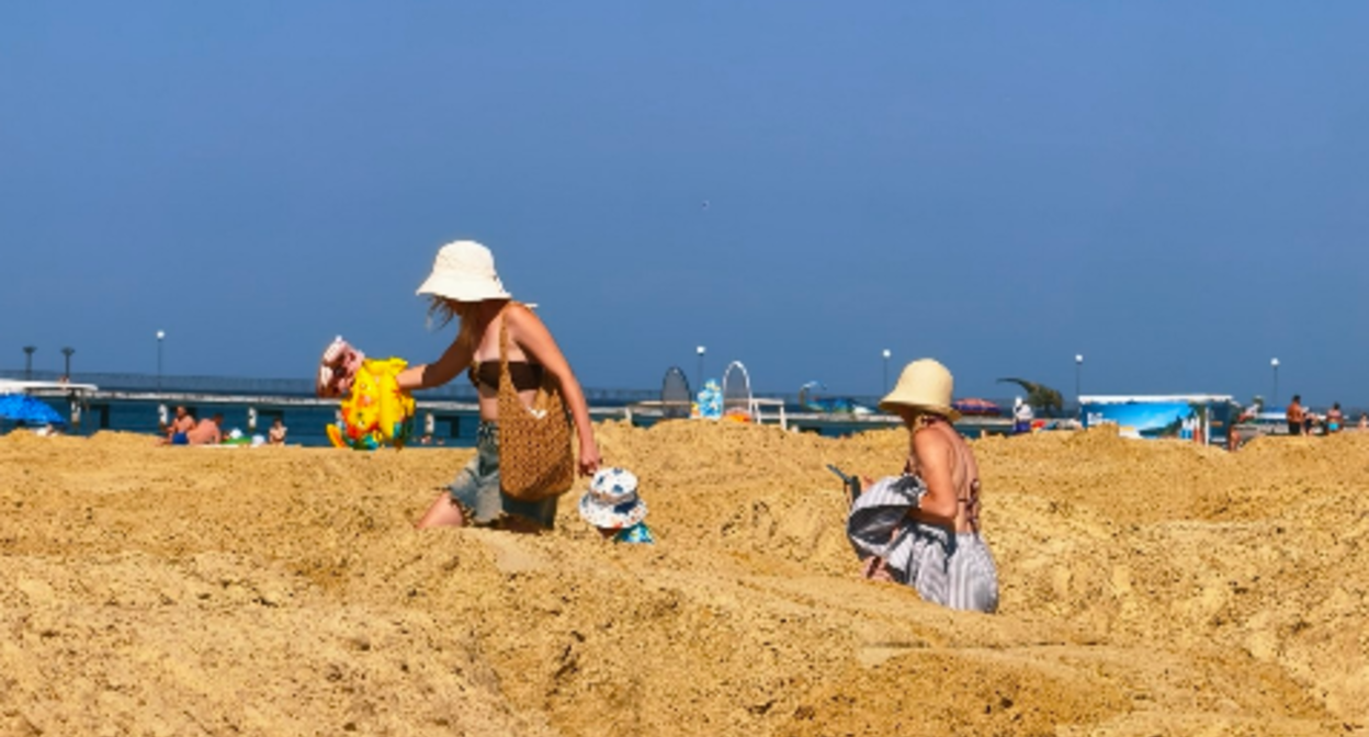 Tourists are making their way among the piles of sand to the beach in Vityazevo. Screenshot photo by Andrey Makovozov from 19.07.26, https://t.me/makovozovy/64553